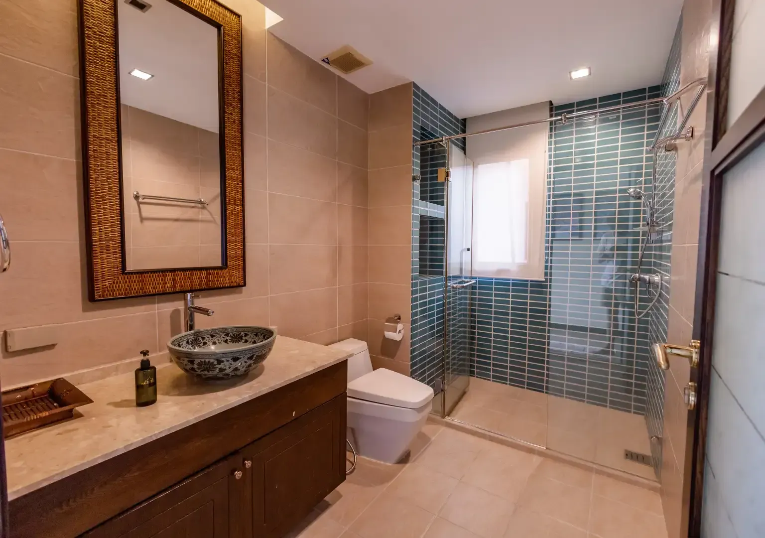 A bathroom with a sink , toilet , mirror and walk in shower.