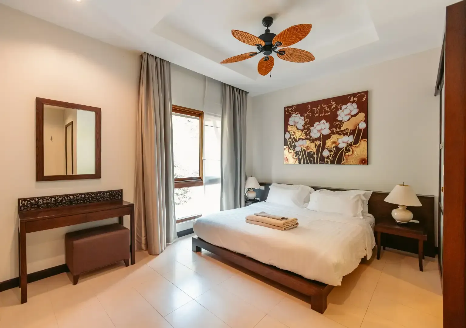 There is a ceiling fan in the bedroom with a large bed.