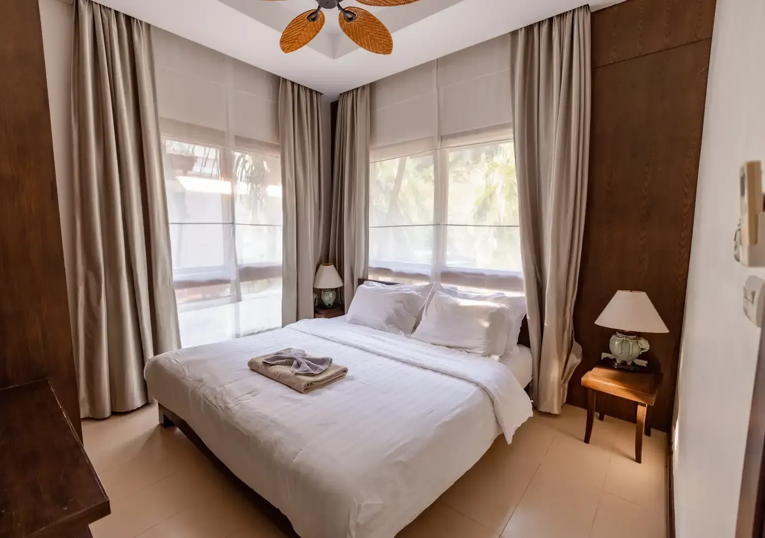 A bedroom with a bed , ceiling fan , curtains and a window.