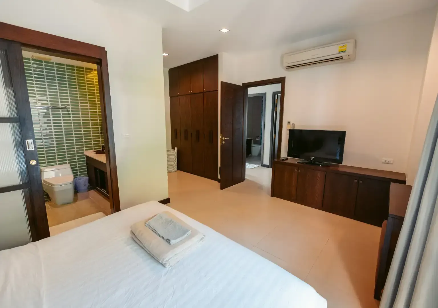 A bedroom with a bed , television , and bathroom.