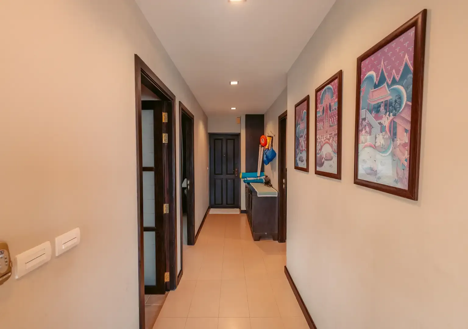 A long hallway with a lot of doors and paintings on the wall.