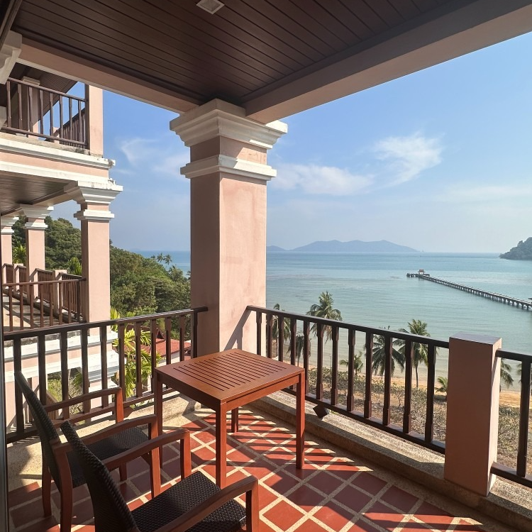 A balcony with a table and chairs overlooking the ocean
