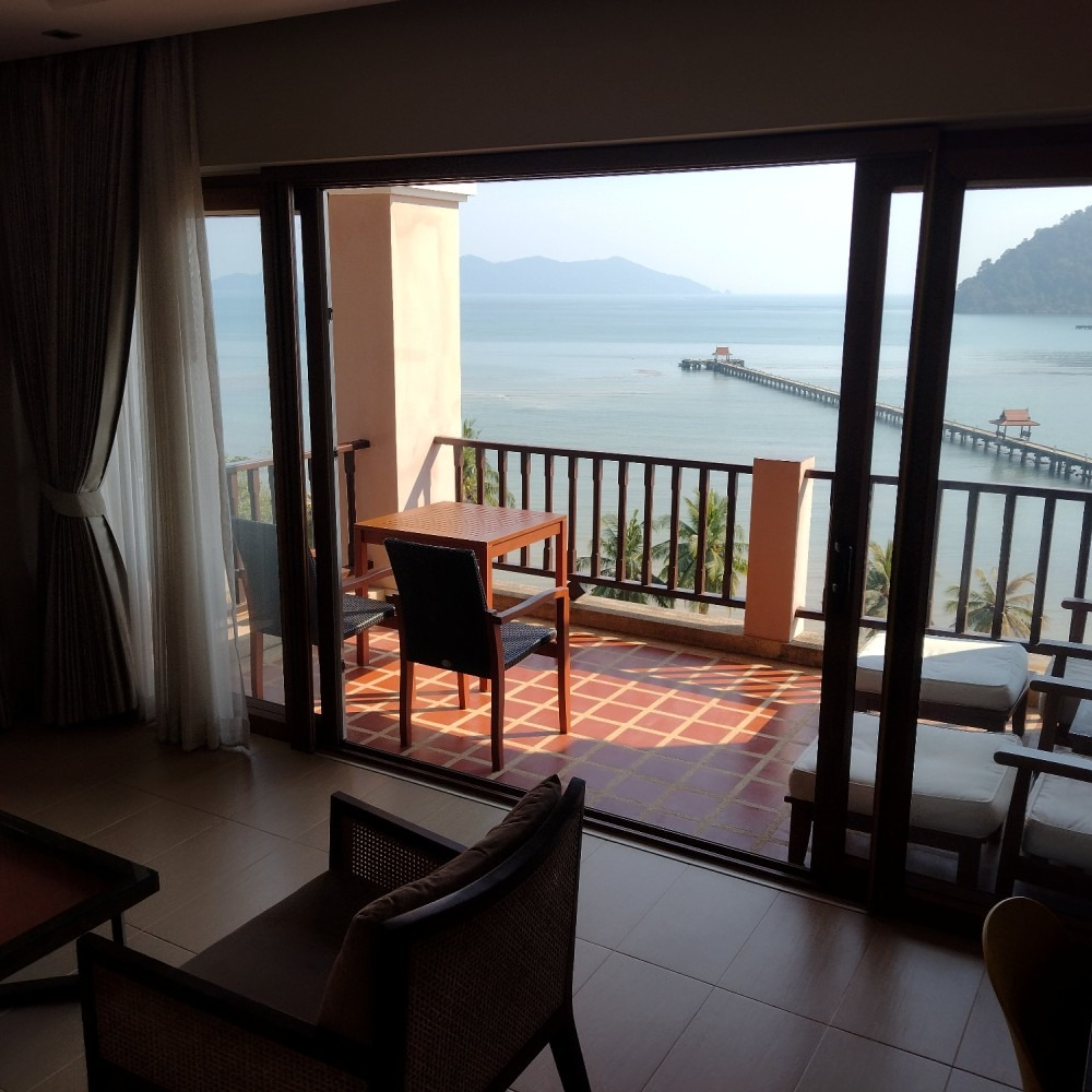A balcony with a table and chairs overlooking the ocean