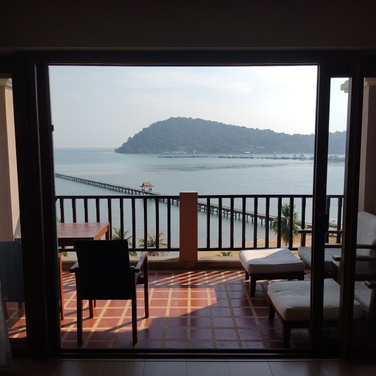 A balcony with a view of the ocean and mountains