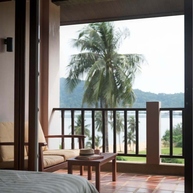 A balcony with palm trees and mountains in the background