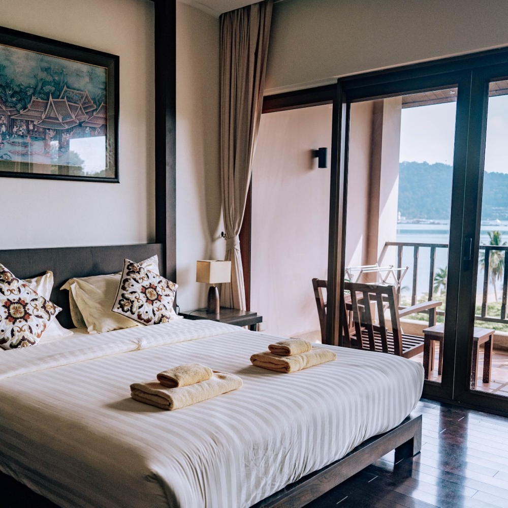 A hotel room with a king size bed and a balcony overlooking the ocean.