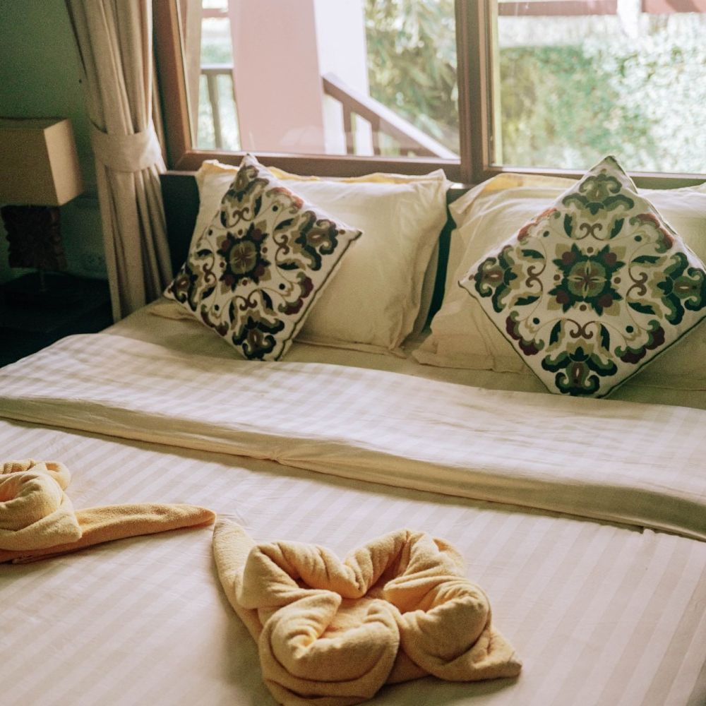 A bed with pillows and a towel shaped like a flower