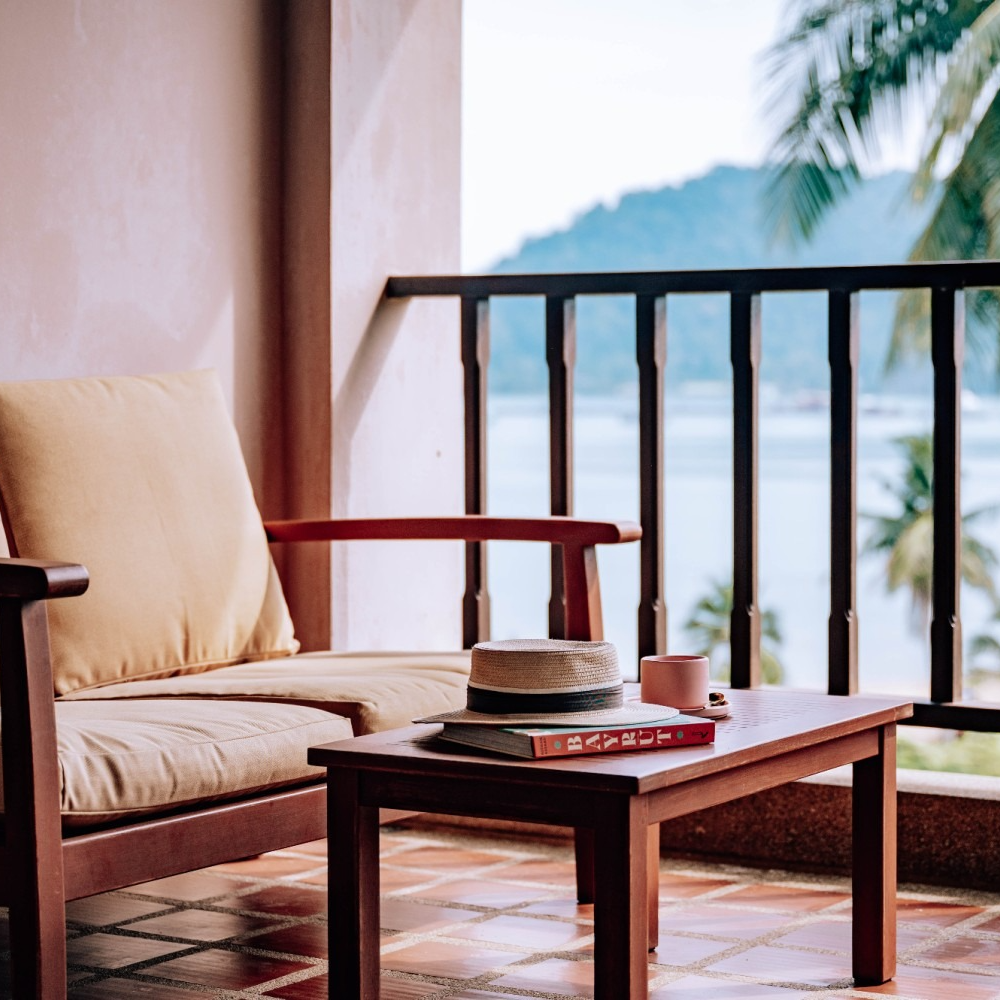 A chair and a table on a balcony with a view of the ocean