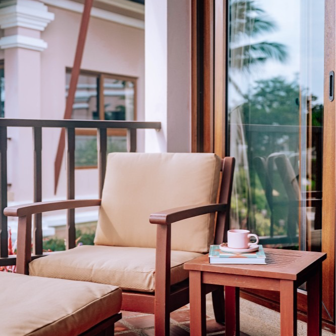 A chair and ottoman on a balcony with a cup of coffee on the table