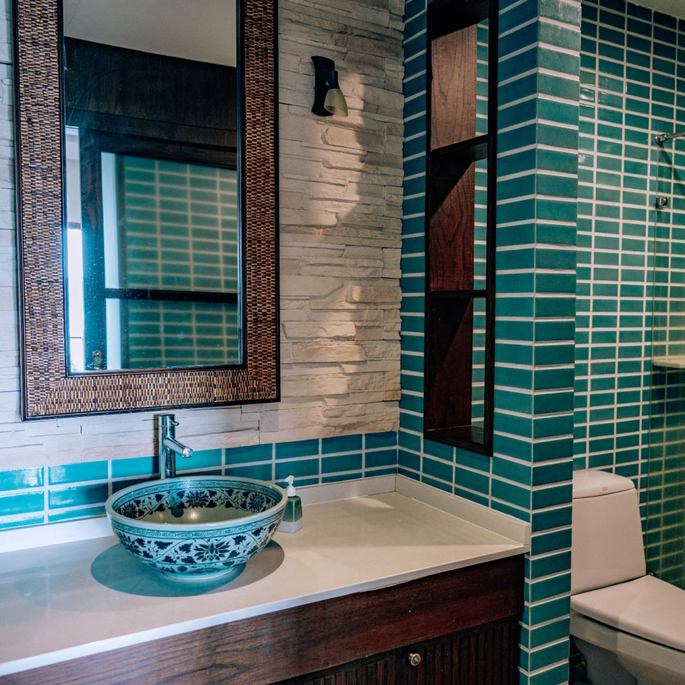 A bathroom with blue tiles and a sink and toilet
