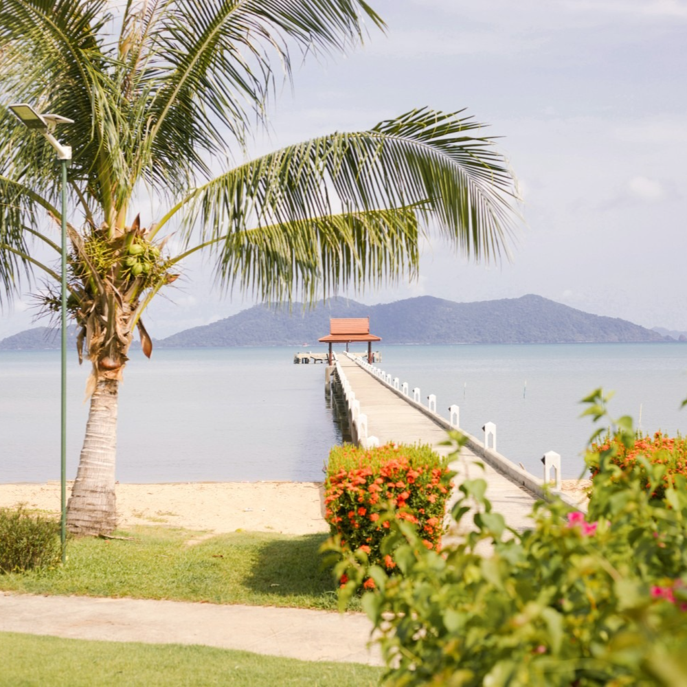 A dock leading to the ocean with mountains in the background
