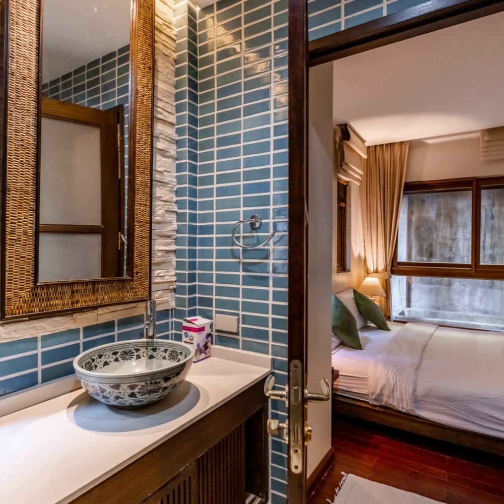 A bathroom with blue tiles and a sink and a mirror