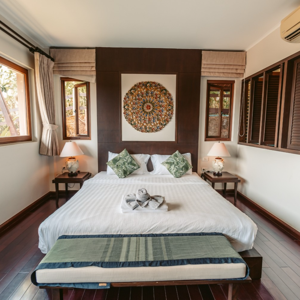 A bedroom with a large bed and a painting on the wall above it
