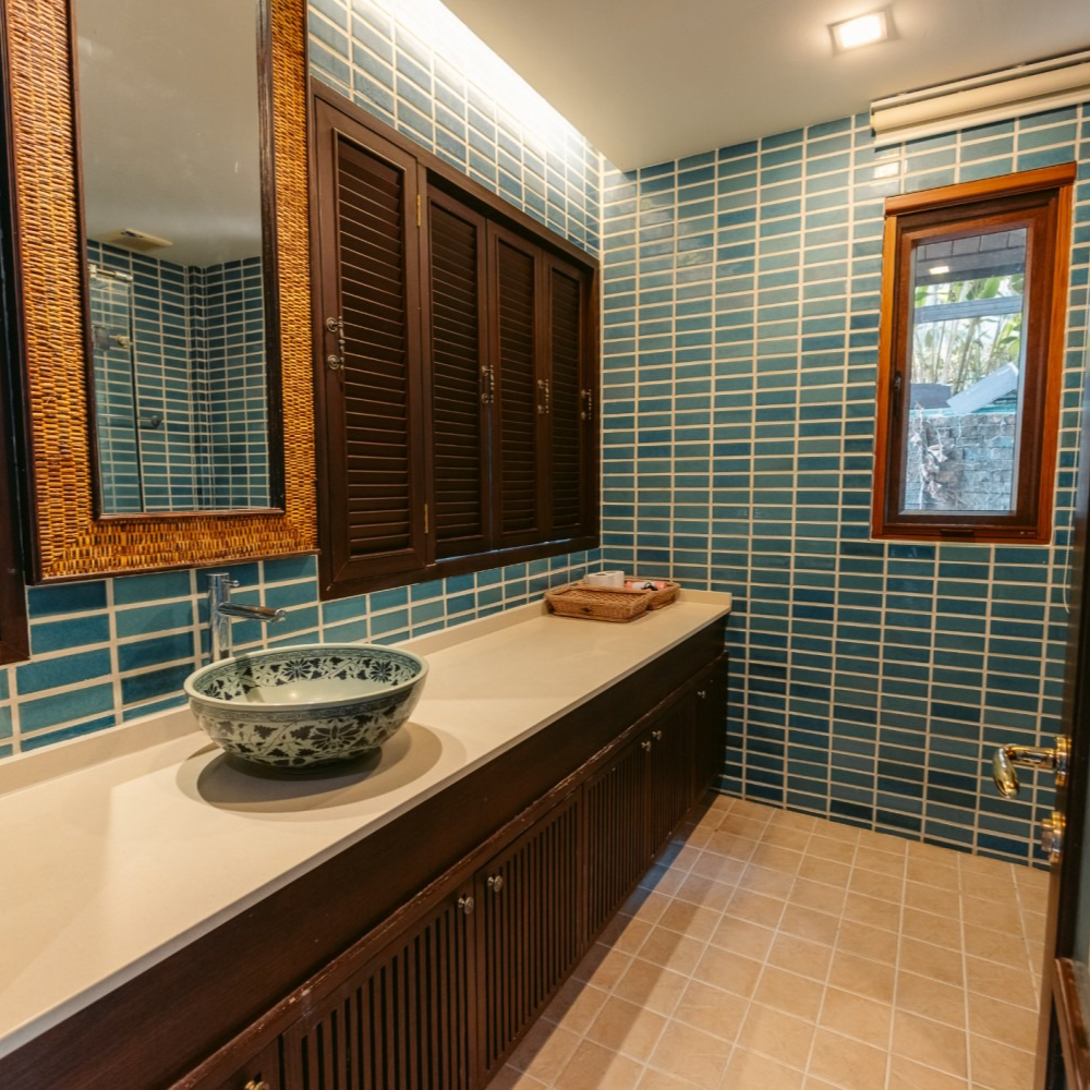 A bathroom with blue tiles and a sink and mirror