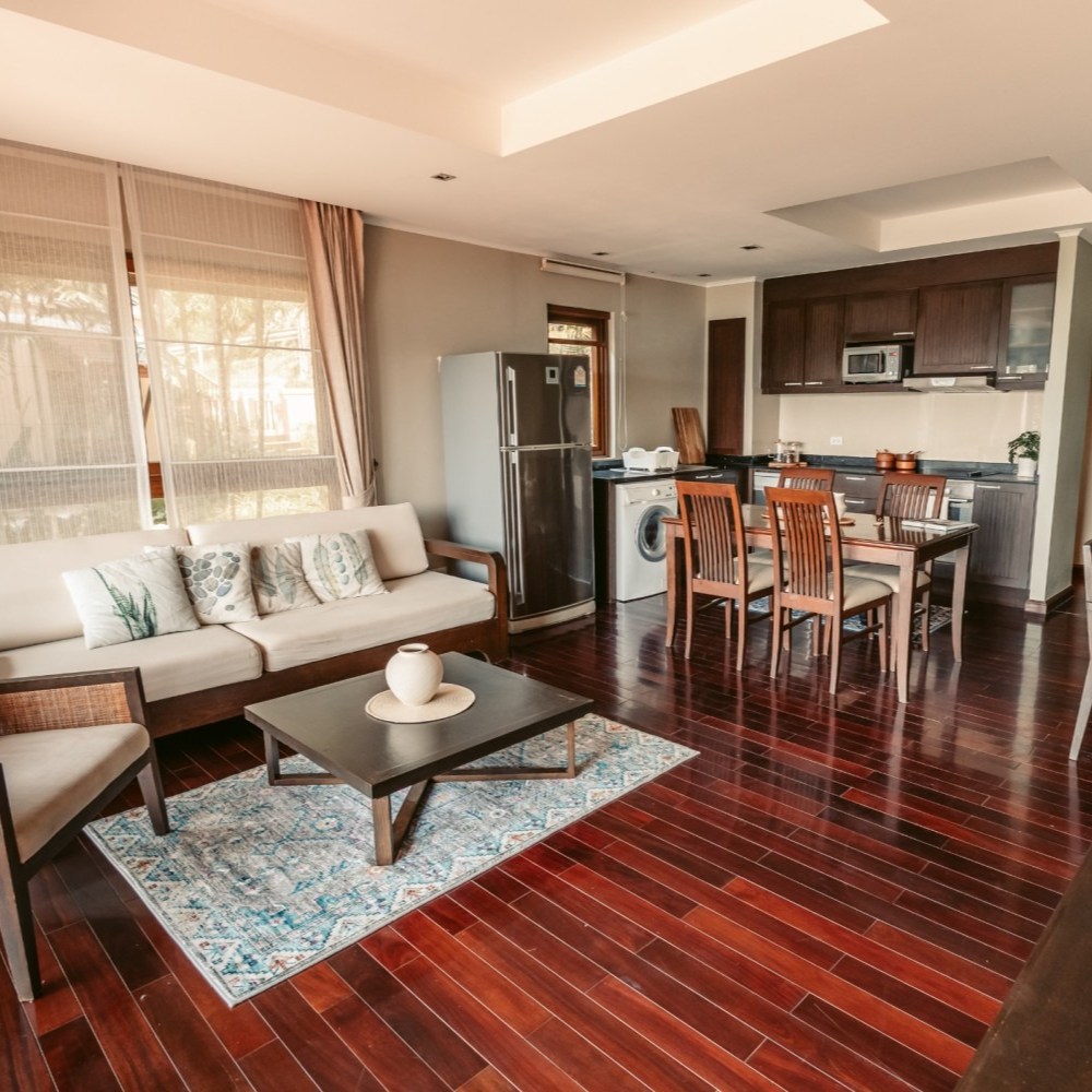A living room with a couch , table , chairs and a refrigerator.