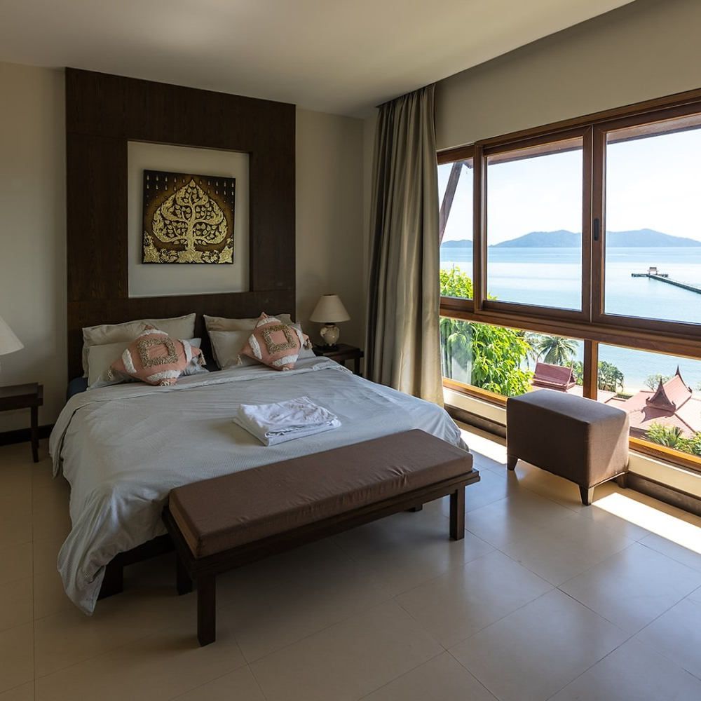 A bedroom with a large bed and a large window overlooking the ocean