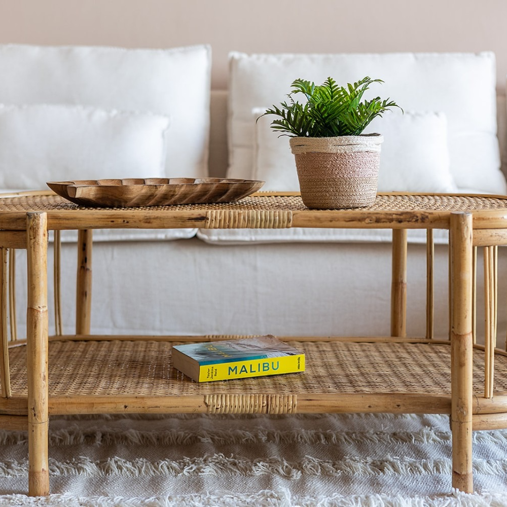 A wicker coffee table with a book titled malibu on it