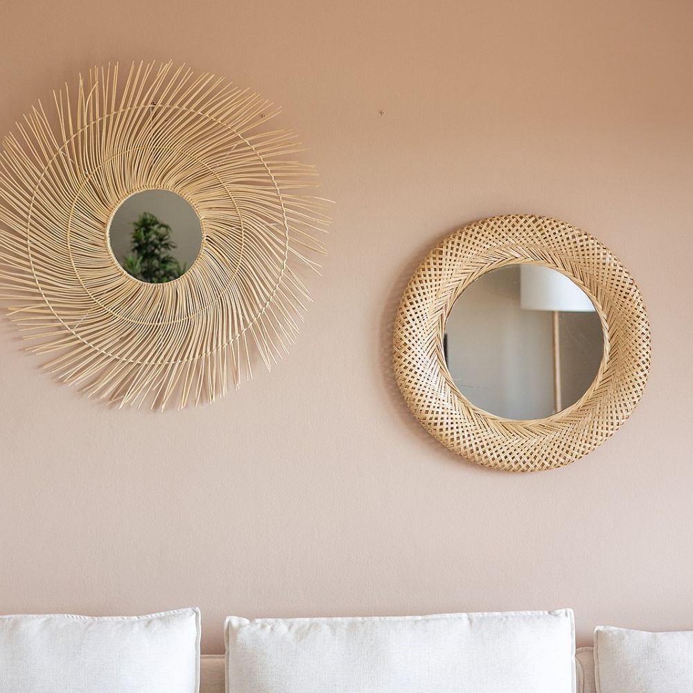 Two mirrors are hanging on a pink wall in a living room.