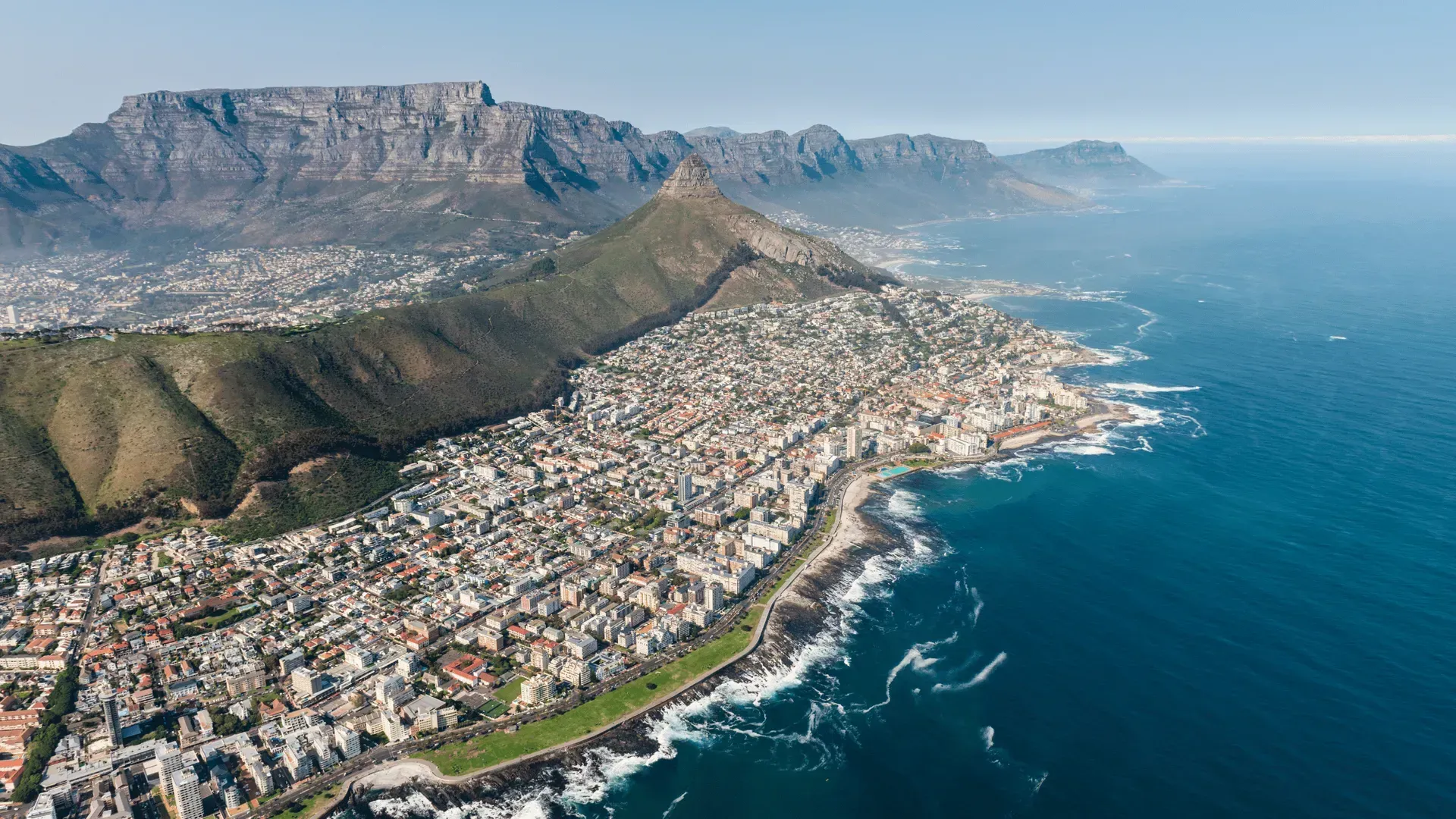 Aerial view of Cape Town with Table Mountain, coastal city, and blue ocean under clear skies