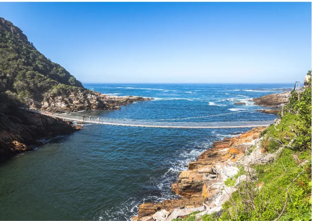 Rocky coastal inlet with blue ocean waves, cliffs, and clear sky