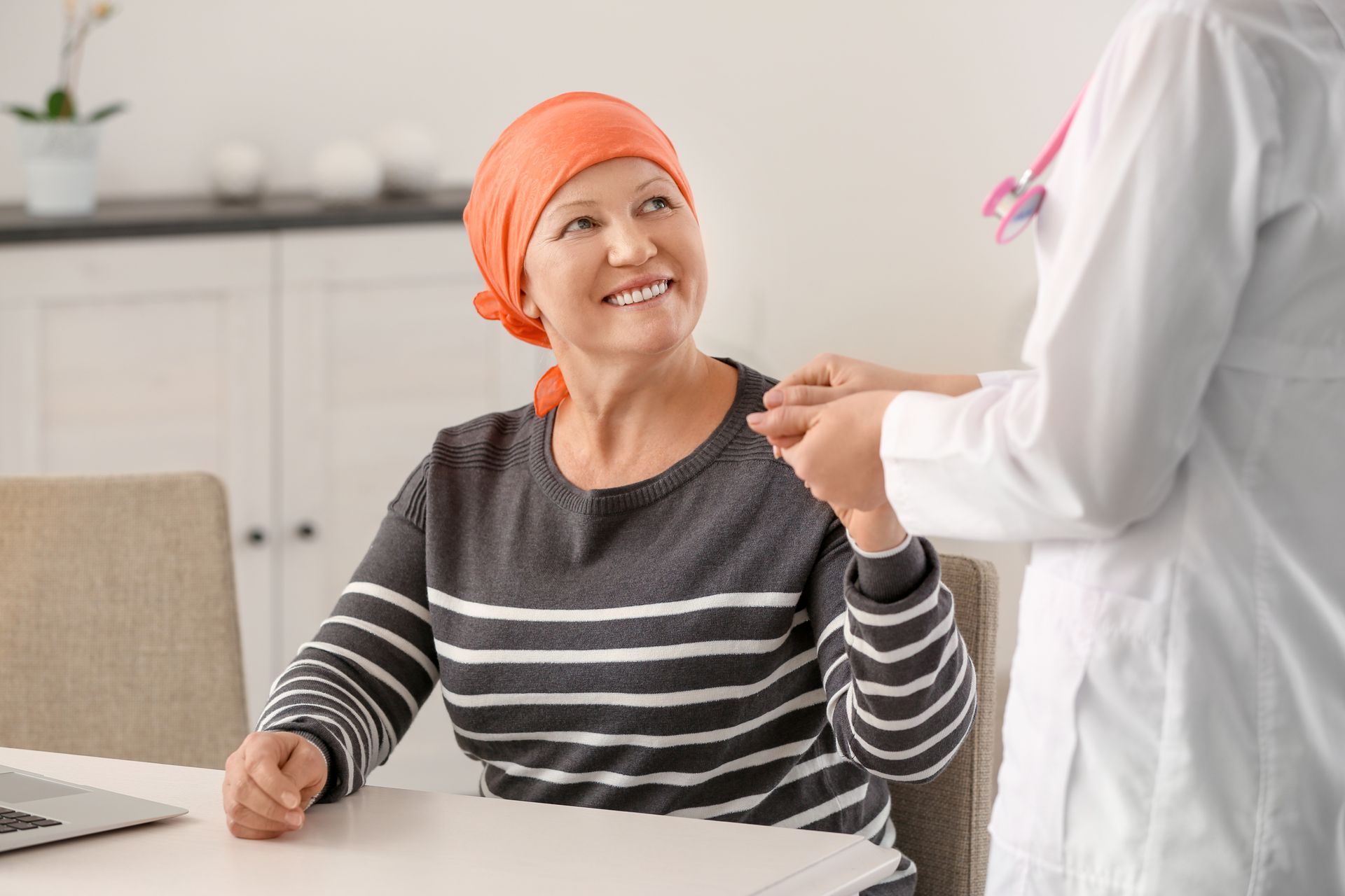 Uma mulher com câncer está sentada à mesa conversando com um médico.