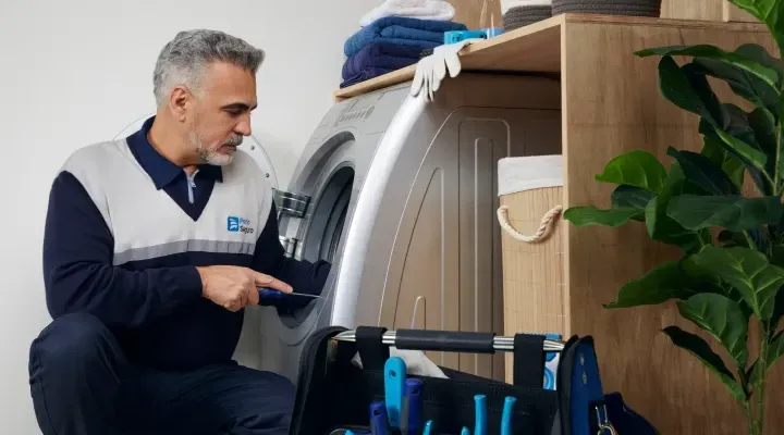 Um homem está consertando uma máquina de lavar em uma lavanderia.