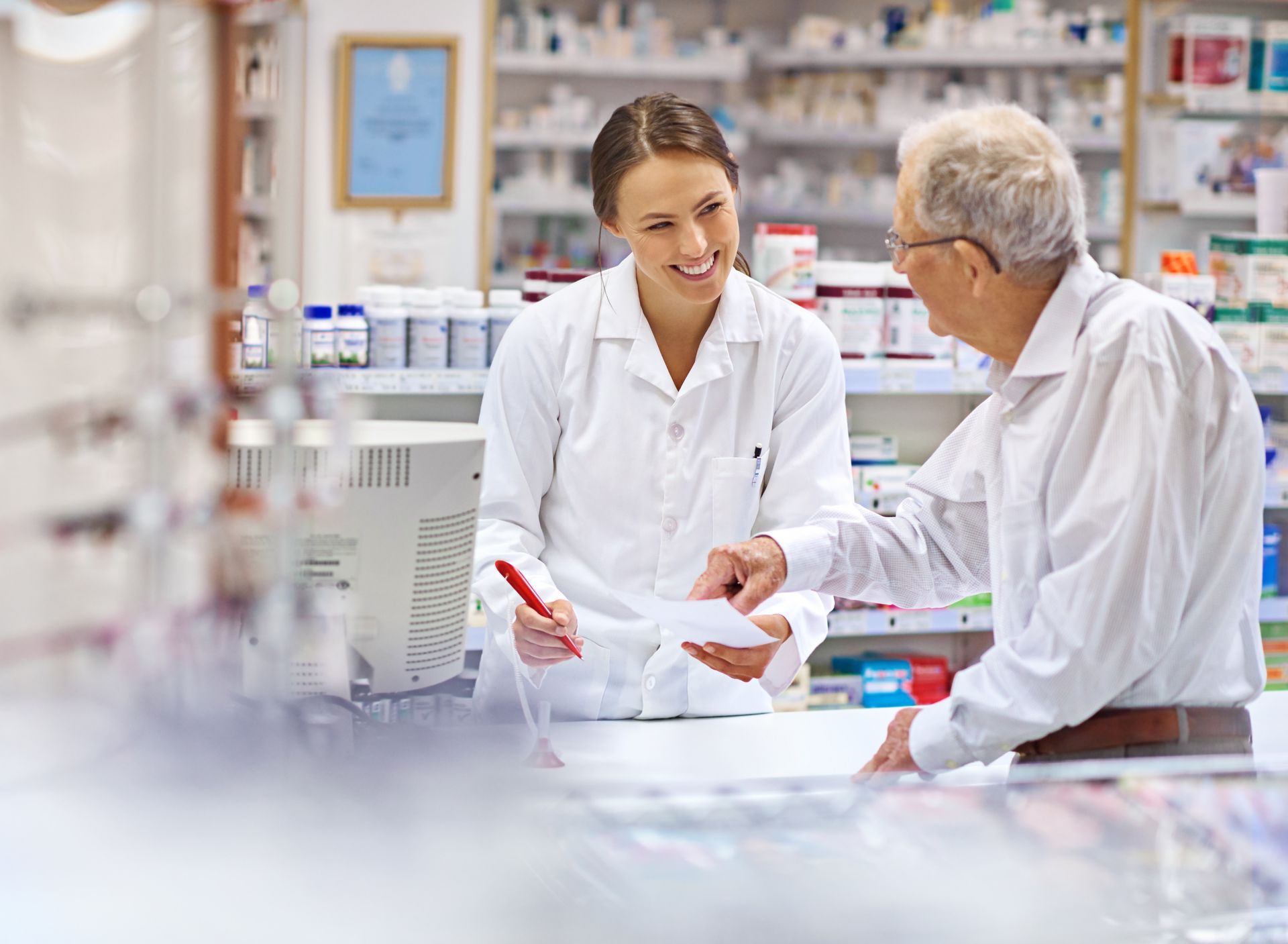 Uma farmacêutica está conversando com um homem mais velho em uma farmácia.