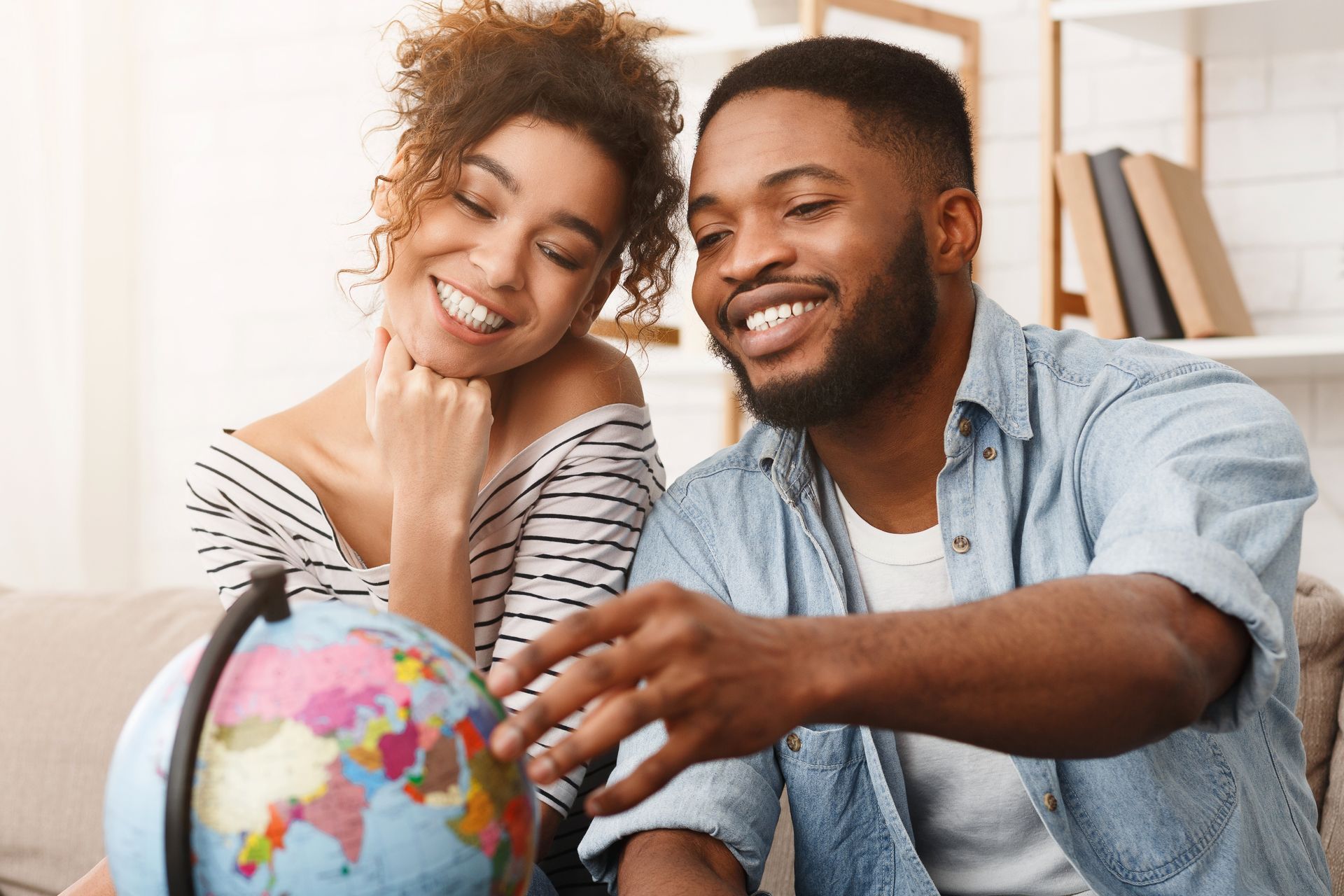 Um homem e uma mulher estão sentados em um sofá olhando para um globo.