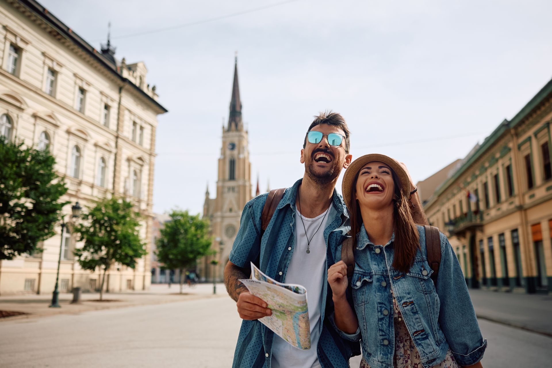 Um homem e uma mulher estão caminhando por uma rua da cidade segurando um mapa.