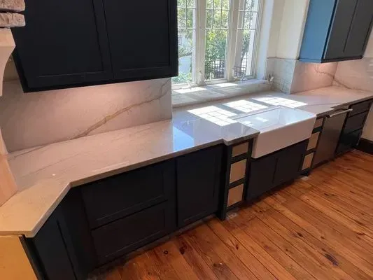 Kitchen with dark blue cabinets, white countertops, and a white farmhouse sink.