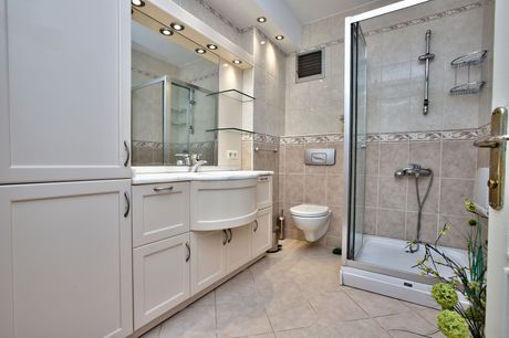 Bright white modern bathroom with glass shower, vanity, mirror, and toilet