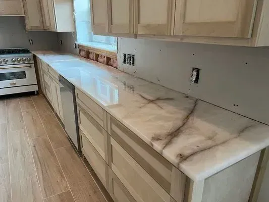 Kitchen remodel with light wood cabinets, white countertops with brown veining, and a stainless steel range.