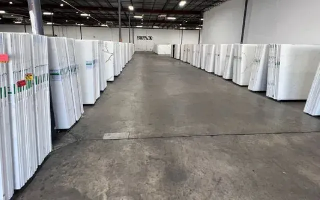 Rows of white material leaning in a warehouse with a gray concrete floor.