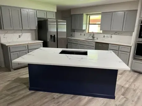 Kitchen with a blue island and gray cabinets, white countertops, and a stainless steel refrigerator.
