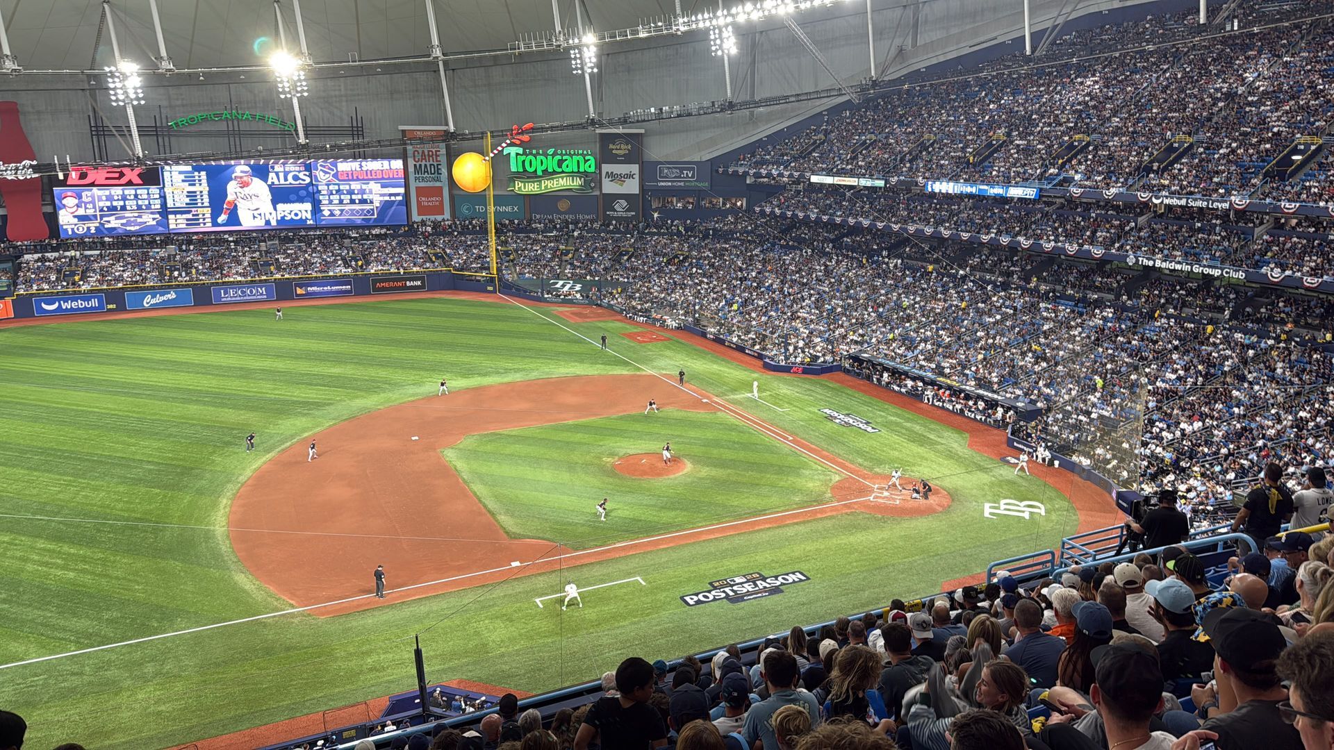 Tropicana Field baseball stadium with a green field, brown infield, and fans filling the stands.