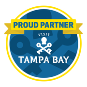 Visit Tampa Bay “Proud Partner” circular blue logo with yellow banner and skull-and-crossbones icon
