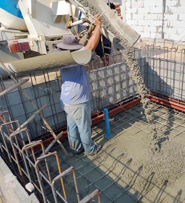 A Man is Pouring Concrete Into a Hole in the Ground — Premier Inspections FNQ In Cassowary Coast, QLD