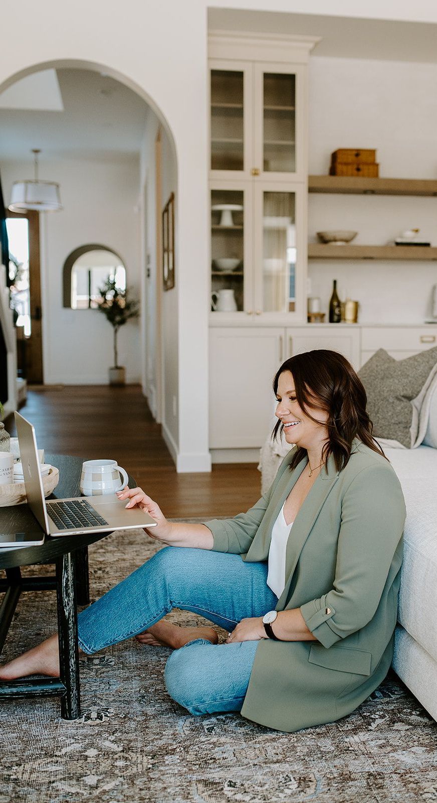 Megan Atamanik is sitting on the floor using a laptop computer.
