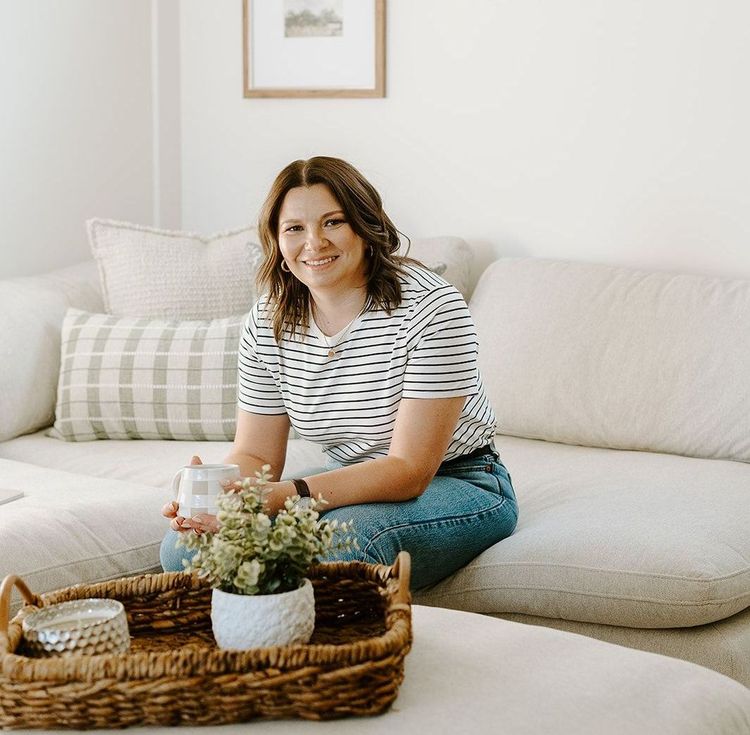 Megan Atamanik is sitting on a couch holding a cup of coffee.