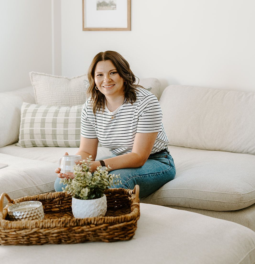 Megan Atamanik is sitting on a couch holding a cup of coffee.