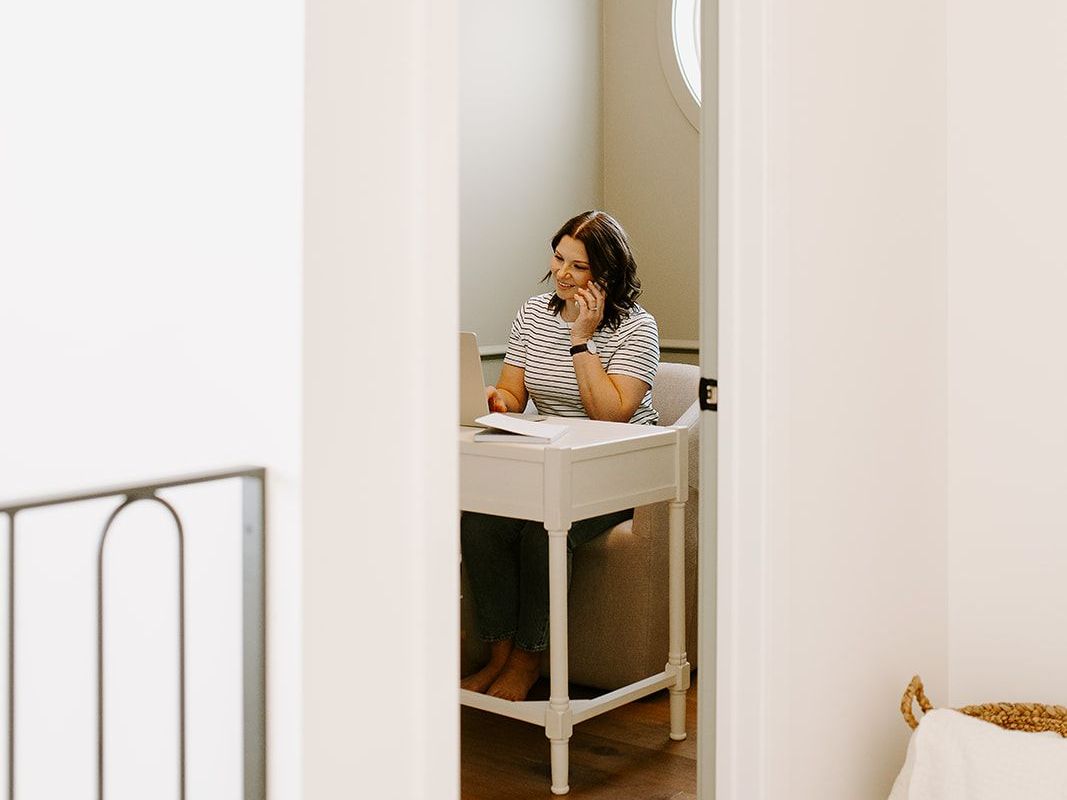 Megan Atamanik is sitting at a desk talking on a cell phone.
