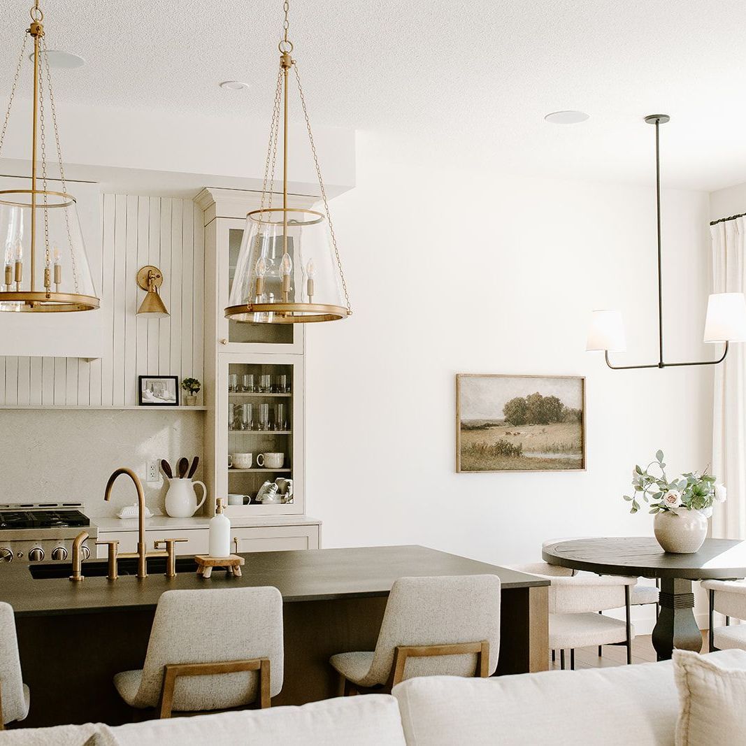 A living room with a couch , chairs , a table and a kitchen.