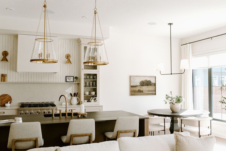 A living room with a couch , chairs , a table and a kitchen.