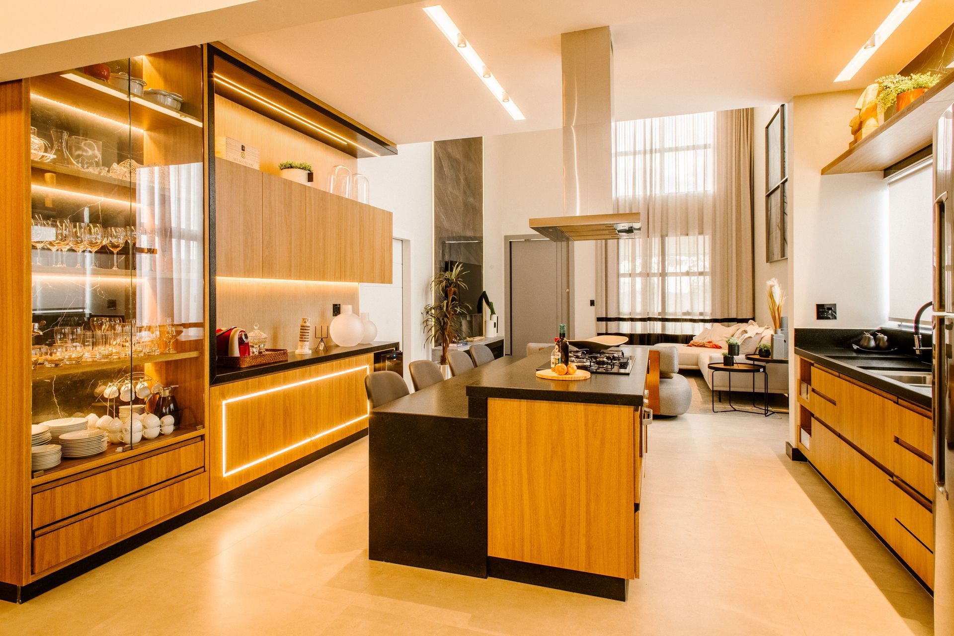 Modern kitchen with wood cabinets, central island, and open dining area with tall windows
