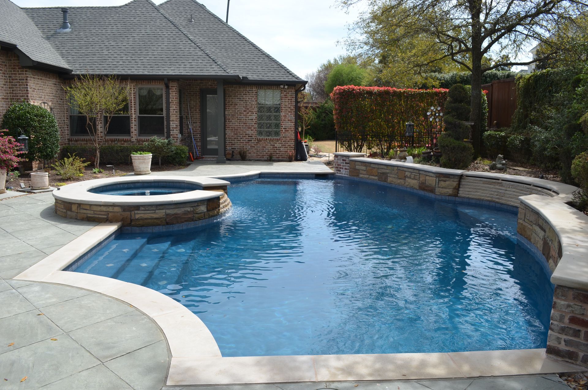 A large swimming pool in front of a brick house