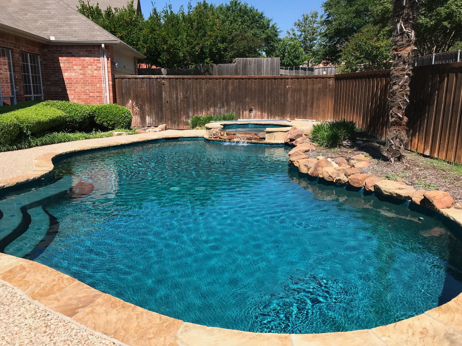 A large swimming pool is in the backyard of a house.