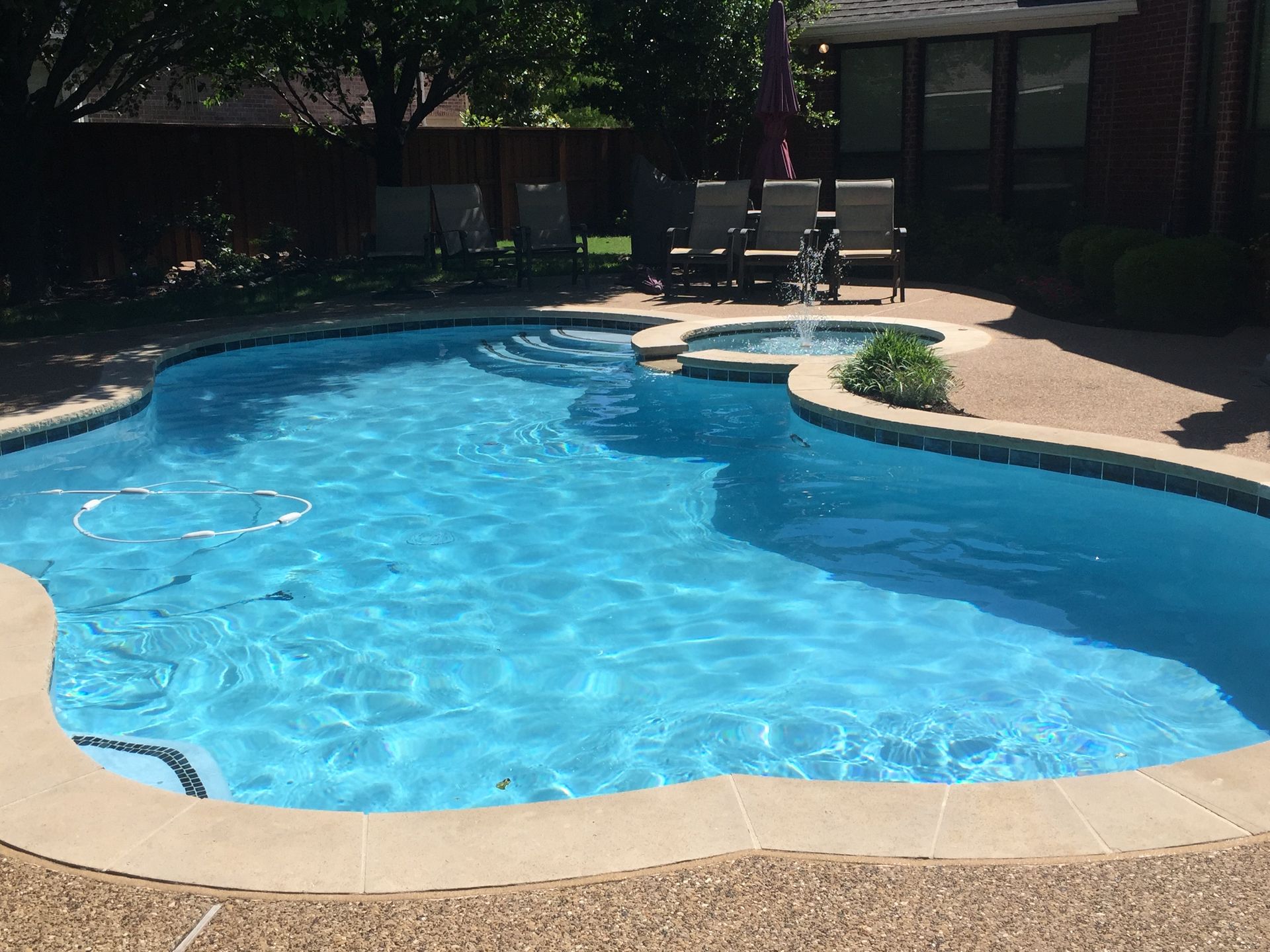 A large swimming pool with a table and chairs in the background