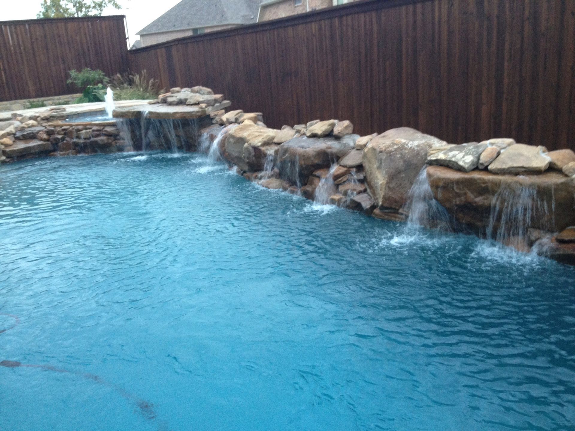 A large swimming pool with a waterfall in the middle