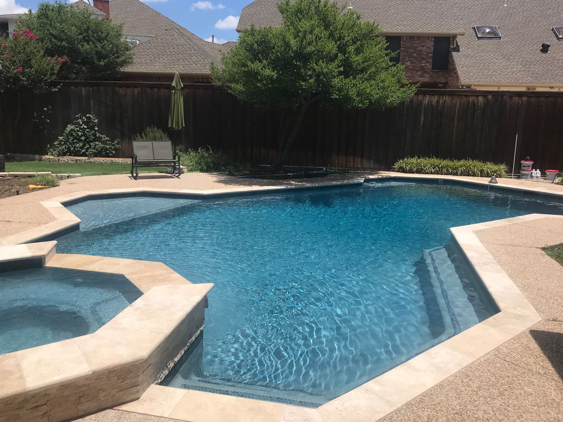 A large swimming pool with a hot tub in the backyard