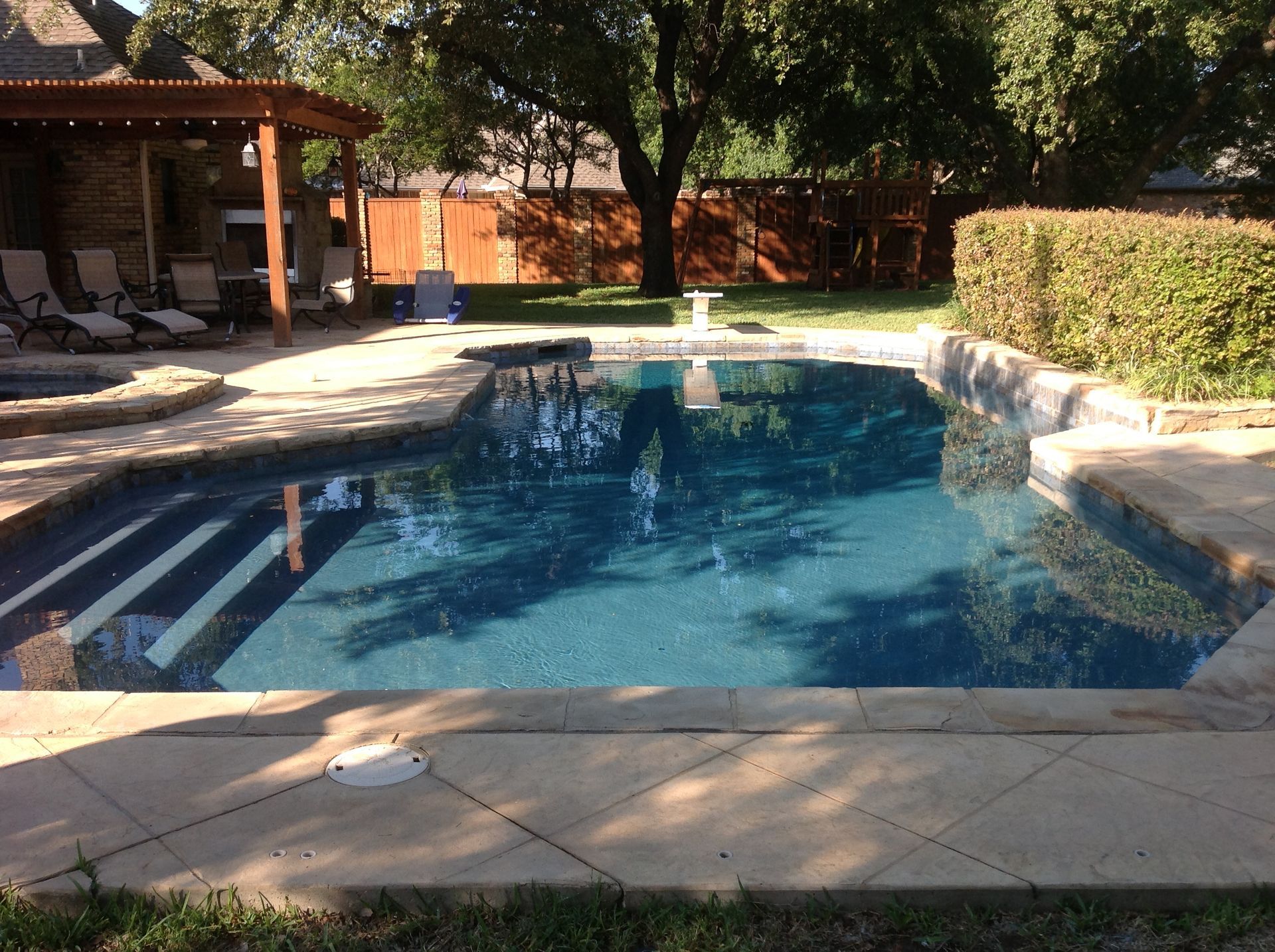 A large swimming pool in a backyard with a pergola